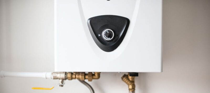 close up of black control knob on white tankless water heater installed in a houston home