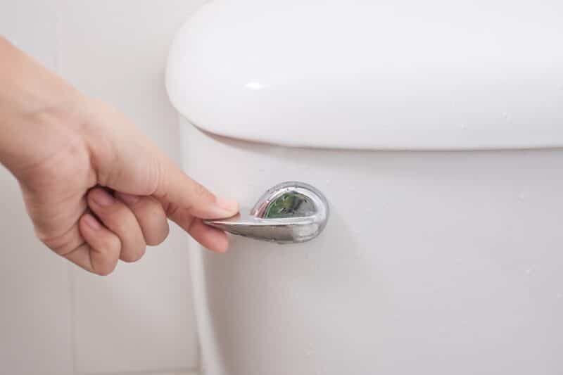 close up of hand flushing a toilet