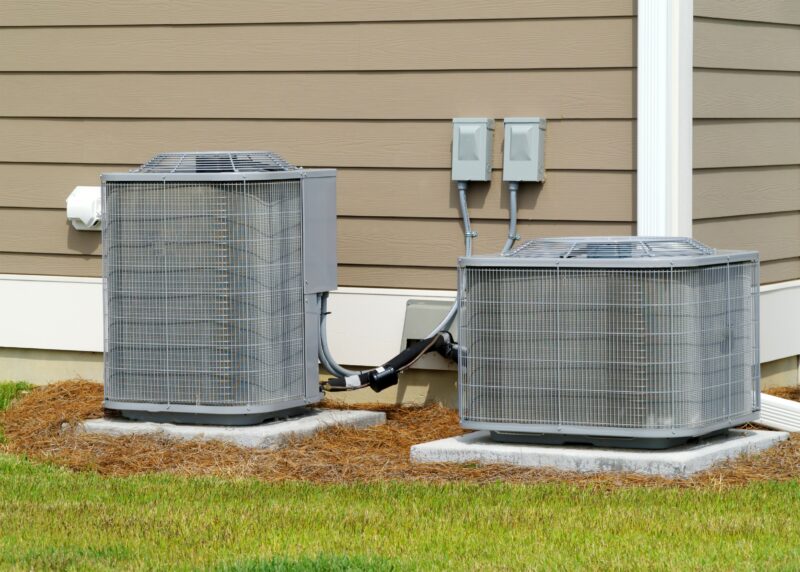 one tall and one short, light gray hvac units installed outside a tan colored home in houston