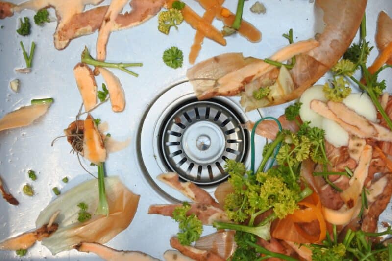 top view of a closed kitchen sink drain surrounded by various vegetable peels