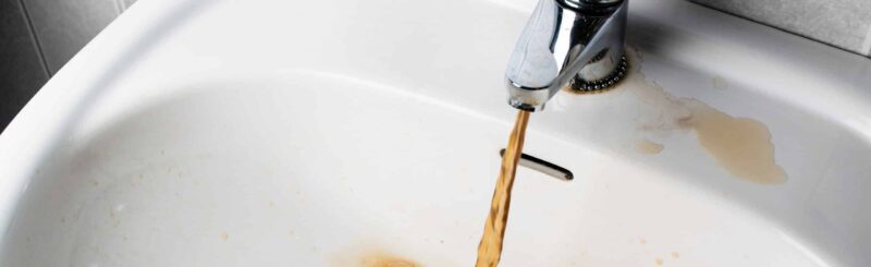 Dirty brown water running into a sink