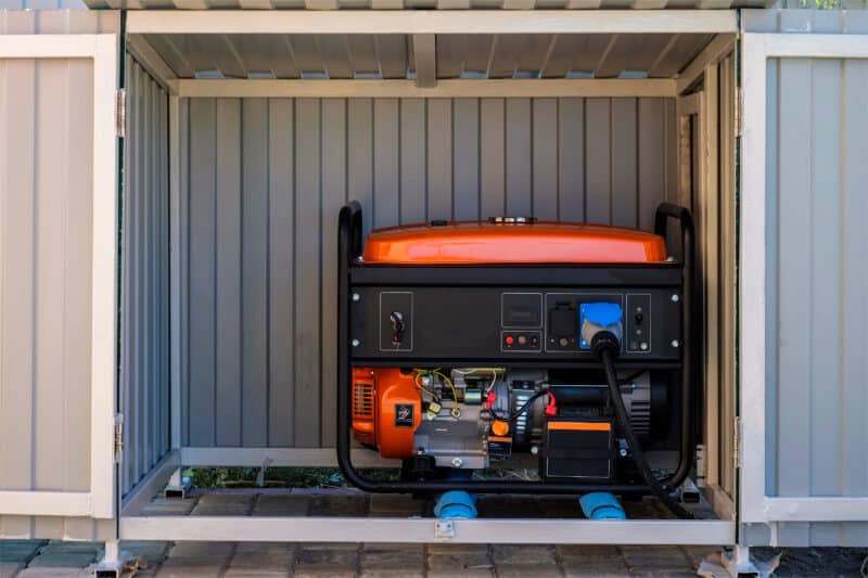 red and black whole-home generator sitting in a metal housing