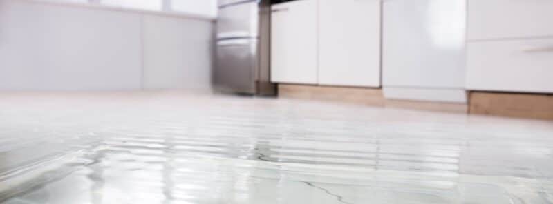 standing water on a kitchen floor near a stove and other electrical applicances